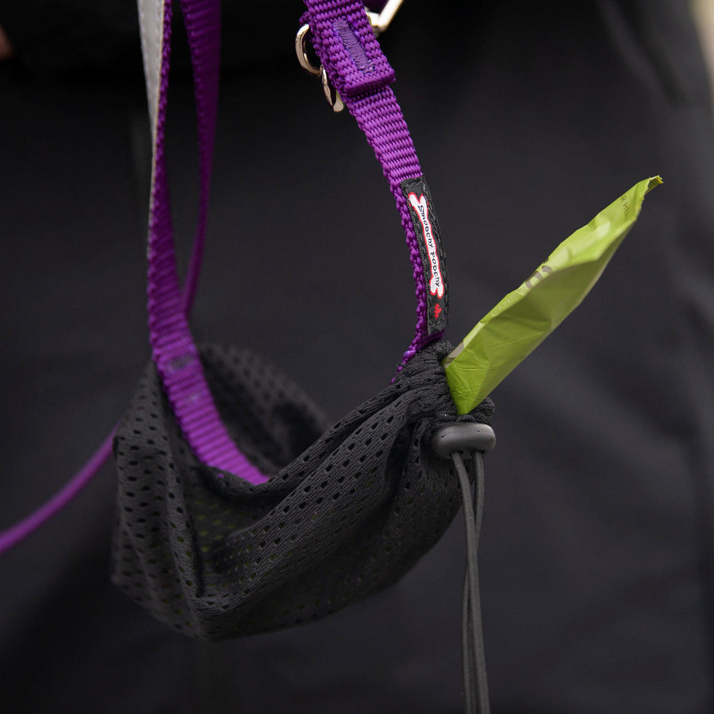 Smoochy Poochy hands-free leash featuring a purple strap and a black mesh pouch with a green waste bag.