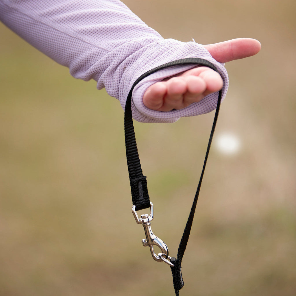 Smoochy Poochy hands-free leash with a black strap and double-ended clip, held by a gloved hand.